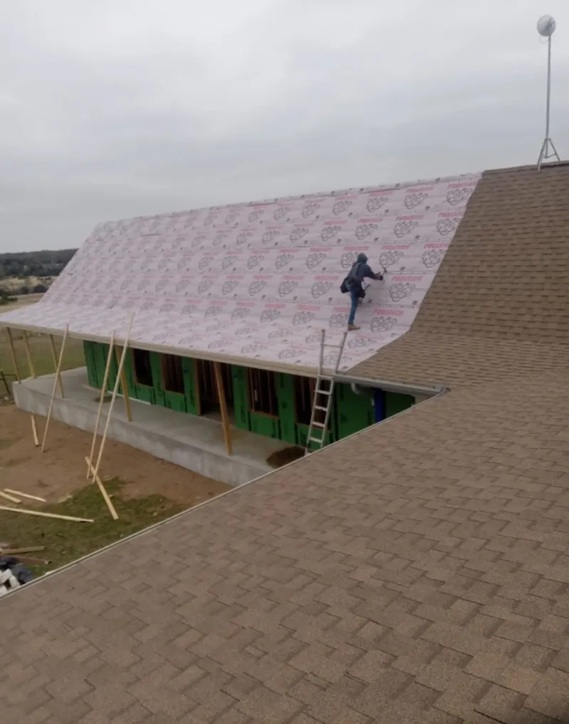 Worker preparing underlayment for a metal roof installation in Blendon